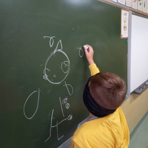 pokaż obrazek - Dziecko rysuje na tablicy